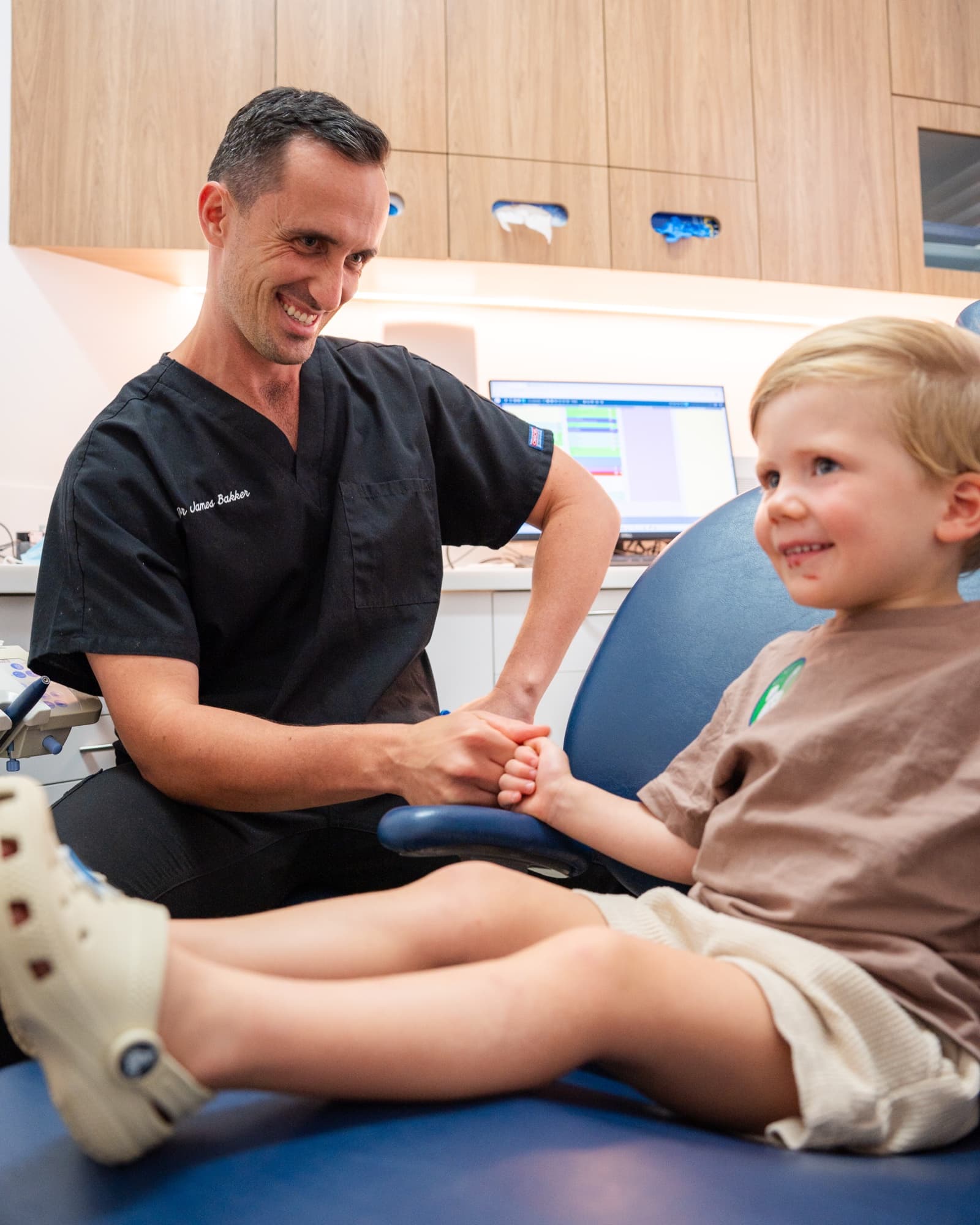 Dr James Bakker greeting a young patient with a handshake in the chair