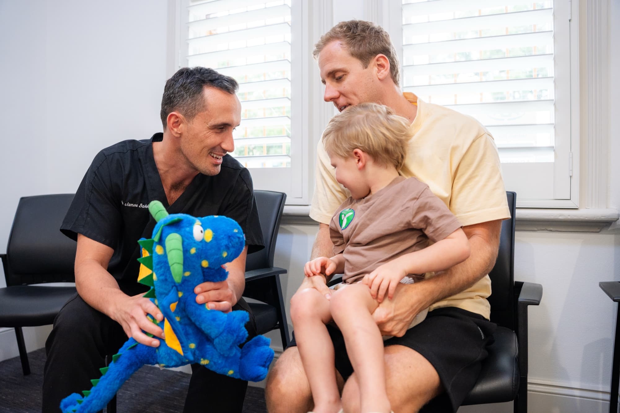 Dr James Bakker with a young child and his dad, dragon puppet brushing demo