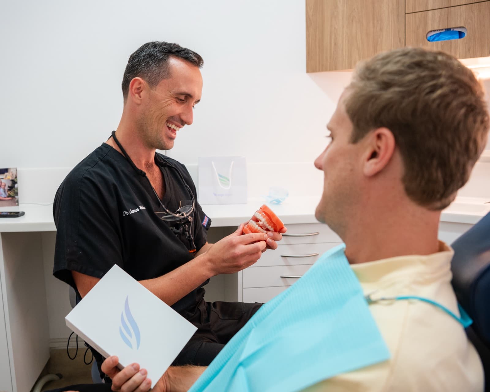 Dr James Bakker discussing a cosmetic plan with a patient using a teeth model